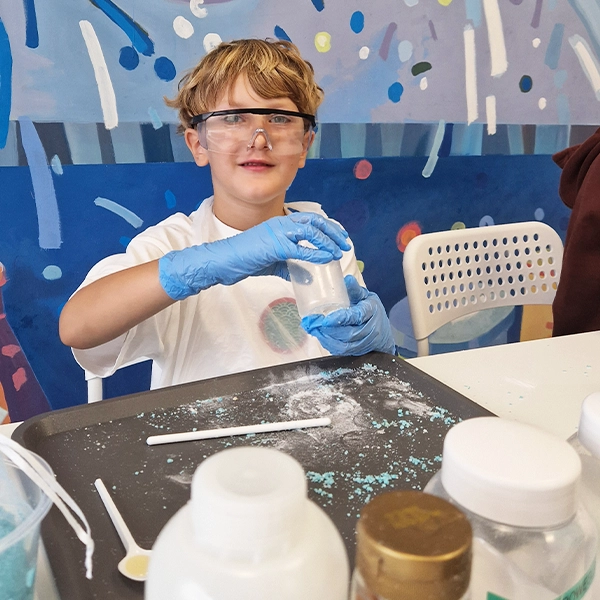 Warsztaty dla przedszkoli Leszno – dzieci w fartuchach i okularach ochronnych robią eksperyment chemiczny